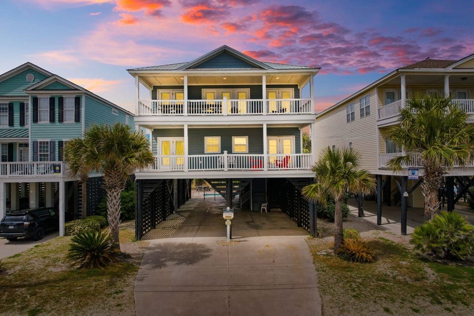 Stunning beach house with dramatic sunset sky creating the perfect coastal getaway backdrop.