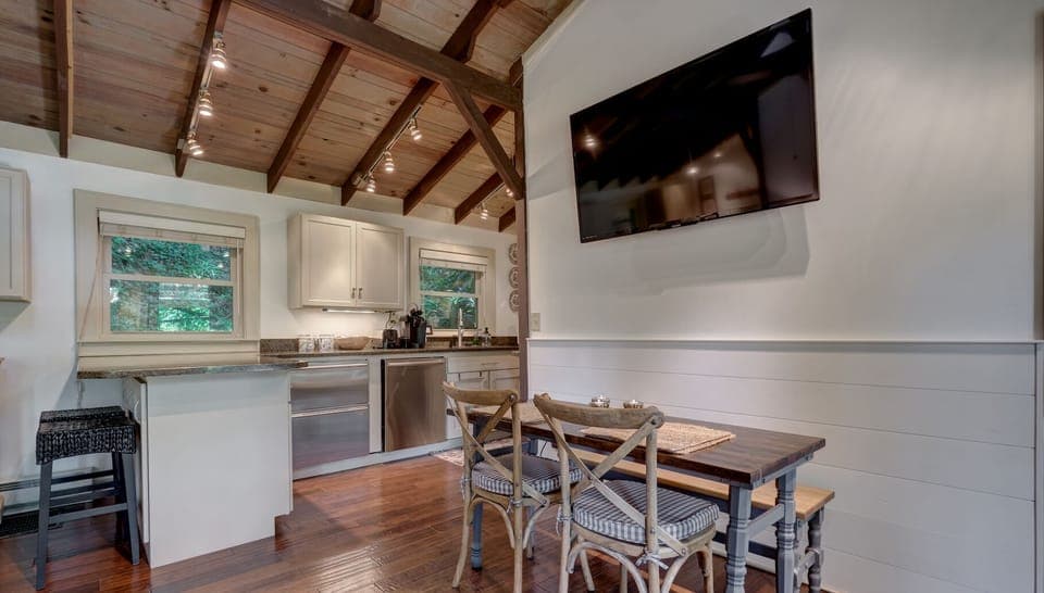 Kitchen and dining table featuring television. The steel appiance on the right side is the dishwasher and the left is the undercounter fridge and freezer.