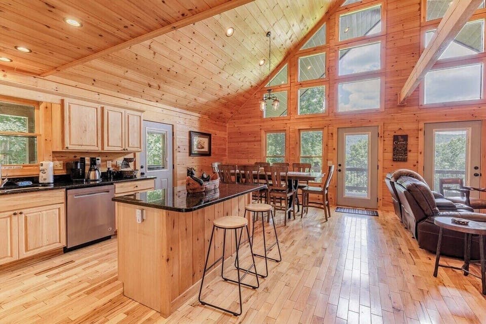 Open kitchen and dining space with vaulted ceilings and large windows filling the room with natural light.