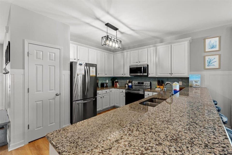 You'll love preparing meals in this fully equipped kitchen with granite countertops, stainless steel appliances, and elegant lighting creating your perfect culinary haven.