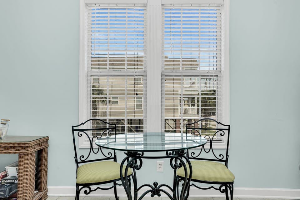 Enjoy your morning coffee at this charming bistro table while soaking up natural light through elegant white blinds.
