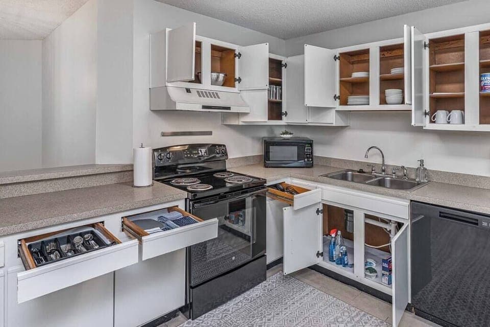 Kitchen is fully stocked with utensils, cutlery, pots, pans, dishes and glassware.