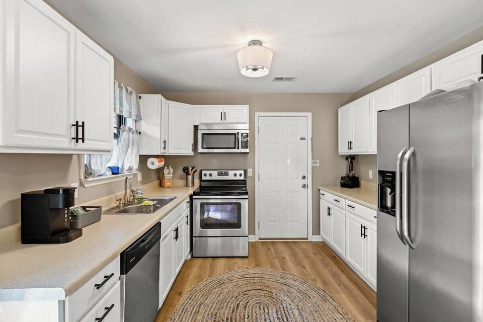 Full sized kitchen stocked with cups, coffee mugs, cooking utensils, silverware and service for 6.