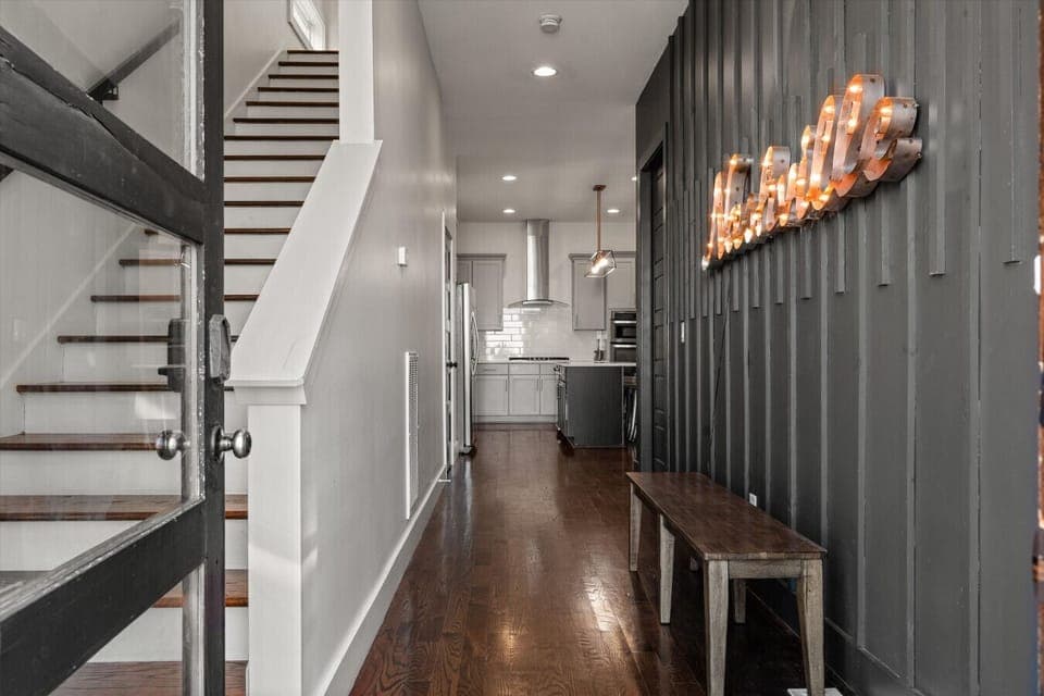 Step inside to warm industrial lighting, rich wood tones, and a clear sight line straight through to the kitchen.