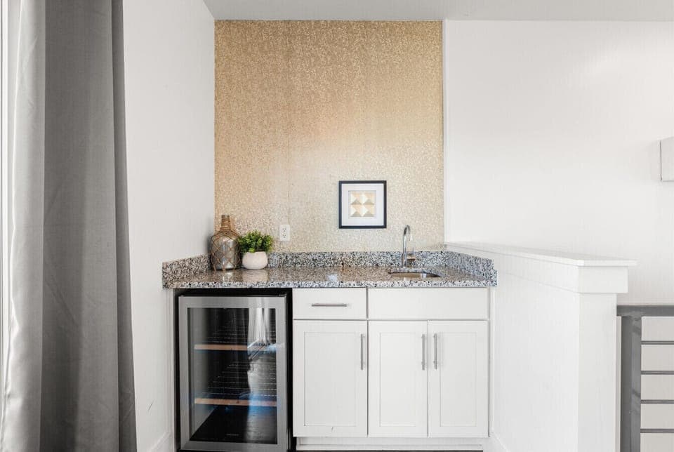 The wet bar on the third level — a mini fridge, and a sink. Pour up before heading to the rooftop.