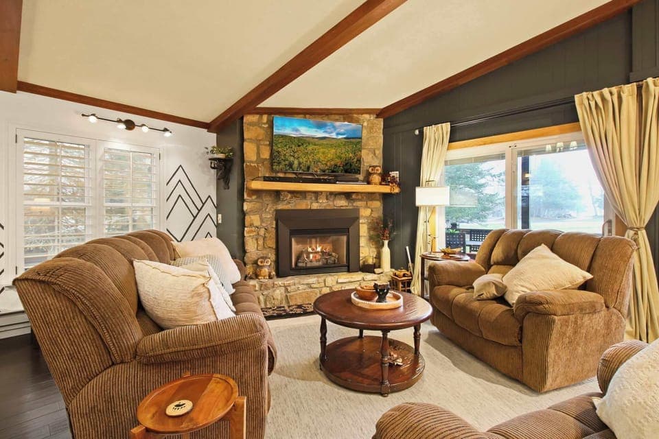 Cozy and welcoming, this open living area boasts a stunning stone fireplace and rustic wood-beam ceilings—an ideal setting for relaxing with loved ones or unwinding in comfort.