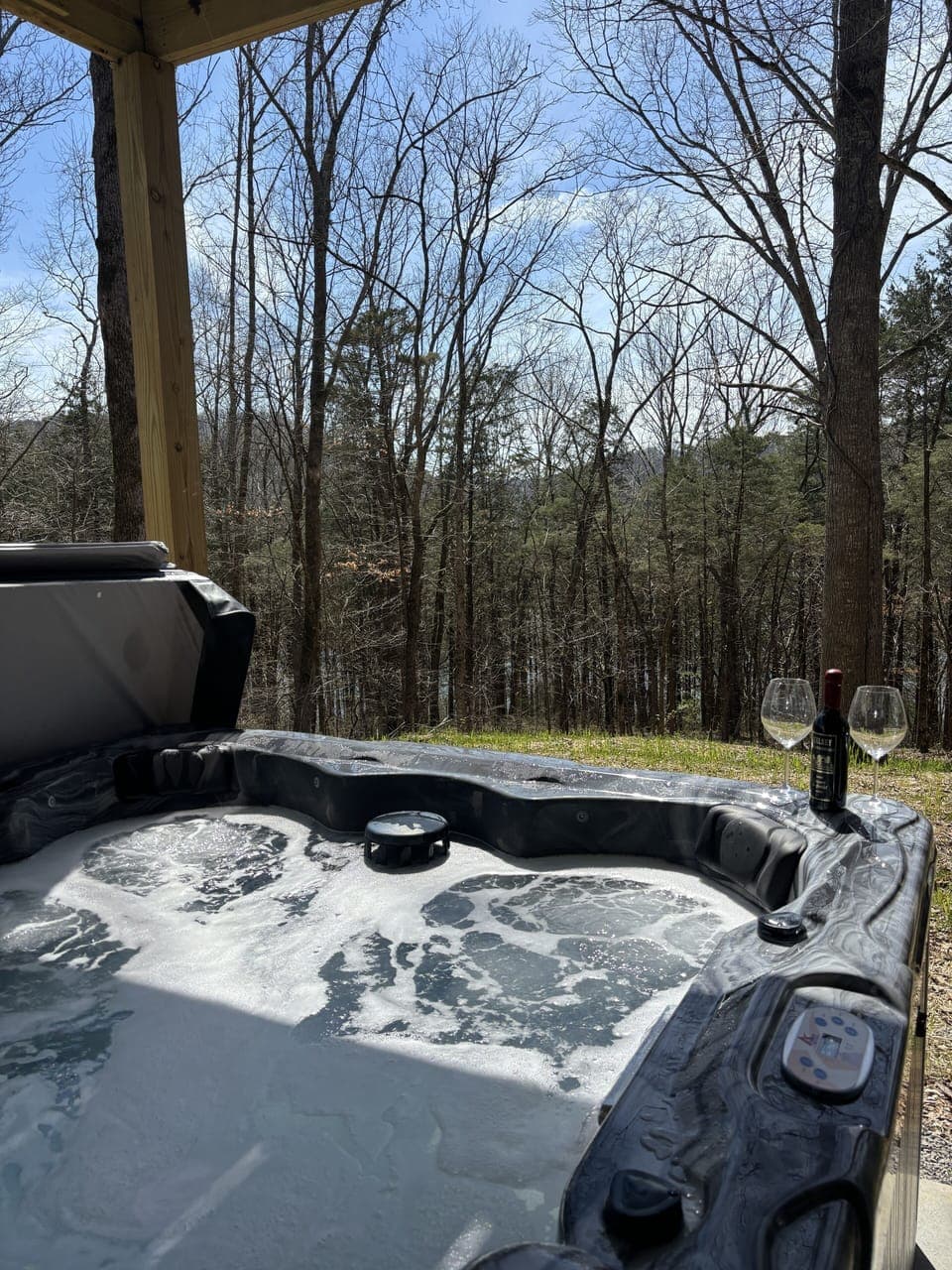 Hot tub on lower patio over looking the backyard & the lake through the trees