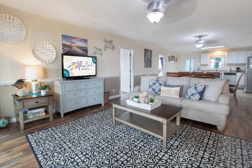 Unwind in this beautifully styled living space featuring cozy seating, coastal décor, and open kitchen access for your perfect beach getaway.