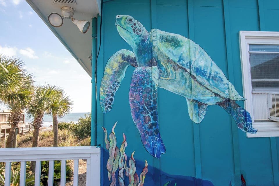 Stunning sea turtle mural greets you at this vibrant coastal property, where ocean-inspired art sets the perfect beachy mood.