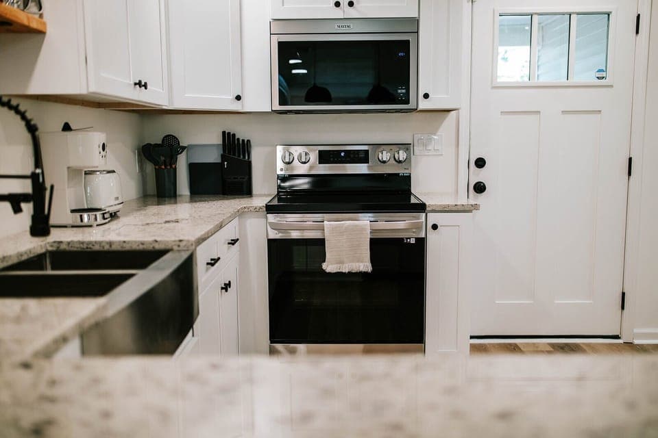 The newly renovated kitchen features modern, stainless steel appliances and bright white cabinets. 
