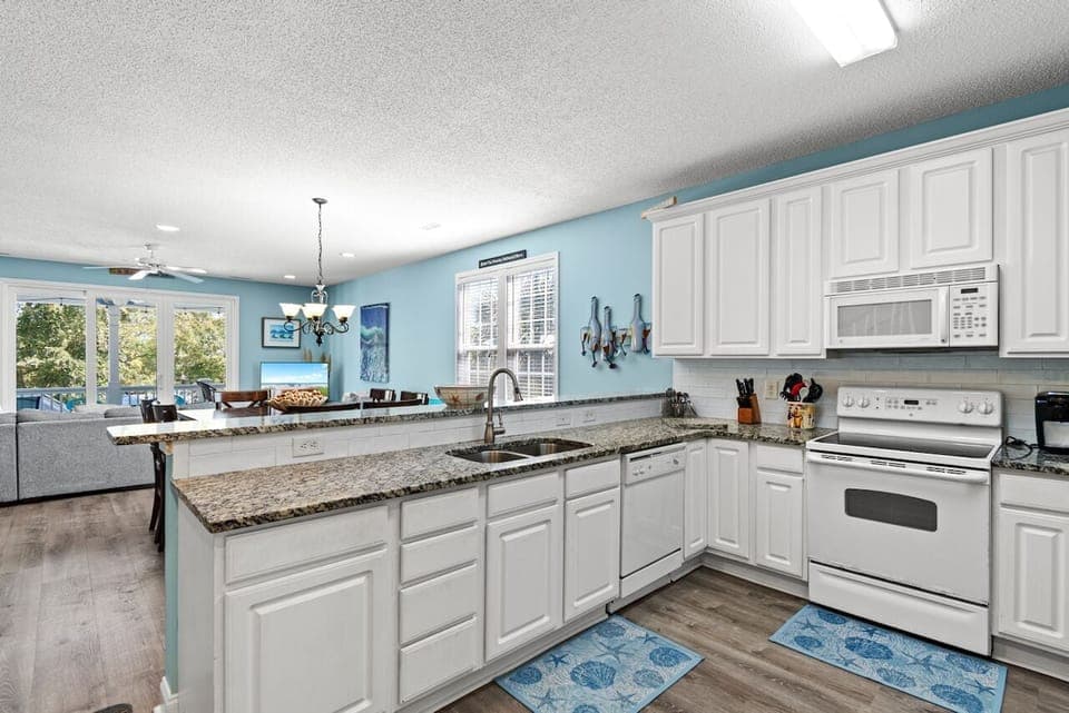 Your spacious kitchen features granite countertops, white cabinetry, and stainless steel appliances, perfect for preparing family meals.