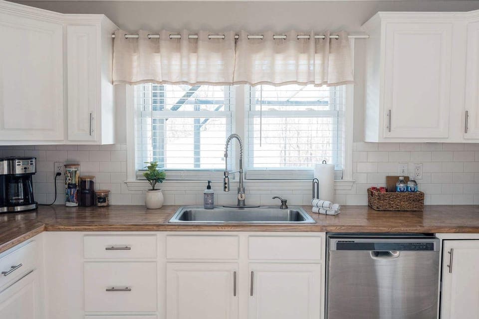 Bright, modern kitchen with stainless steel appliances, white cabinetry, and warm wood countertops. Clean, inviting space with plenty of natural light—perfect for cooking and gathering.