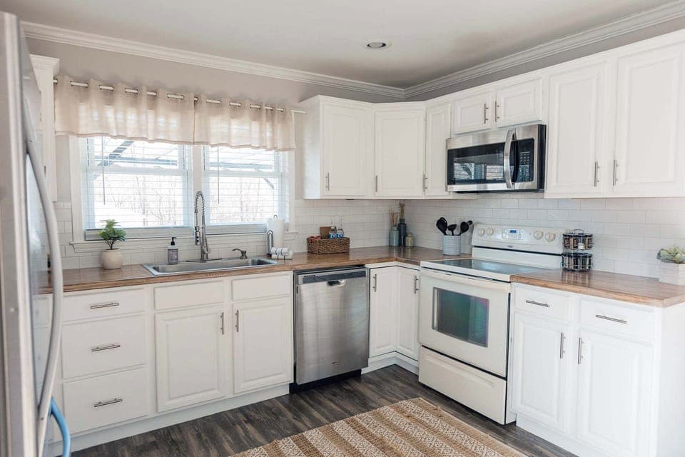 Bright, modern kitchen with stainless steel appliances, white cabinetry, and warm wood countertops. Clean, inviting space with plenty of natural light—perfect for cooking and gathering.